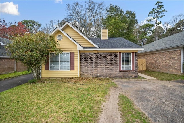 single story home featuring brick siding, a chimney, and a front lawn