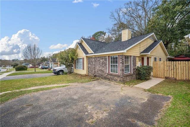 view of home's exterior featuring brick siding, a yard, a chimney, and fence