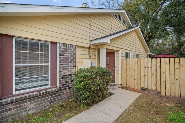 doorway to property with fence and brick siding