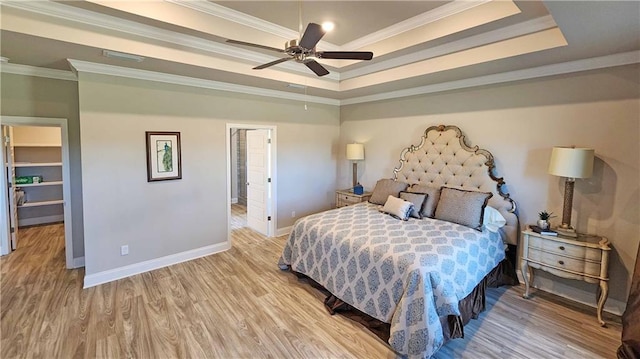 bedroom featuring ceiling fan, light hardwood / wood-style floors, a raised ceiling, and crown molding