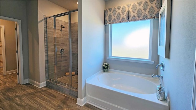 bathroom featuring plus walk in shower and wood-type flooring