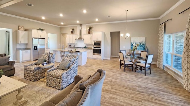 living room with light hardwood / wood-style floors, ornamental molding, and a notable chandelier