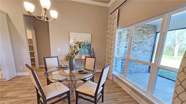 dining area featuring wood-type flooring, ornamental molding, and a notable chandelier