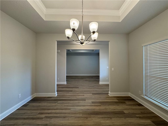 unfurnished dining area featuring ornamental molding, dark hardwood / wood-style flooring, a raised ceiling, and a notable chandelier