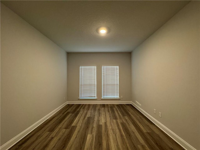 unfurnished room with dark hardwood / wood-style flooring and a textured ceiling