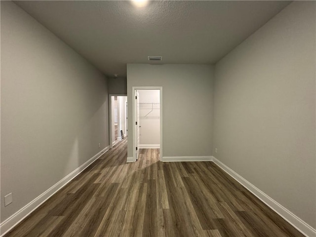 unfurnished room featuring a textured ceiling and dark hardwood / wood-style flooring