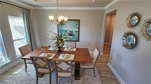 dining space with a chandelier, crown molding, and wood-type flooring