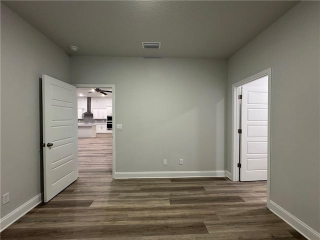 empty room with dark hardwood / wood-style flooring and ceiling fan