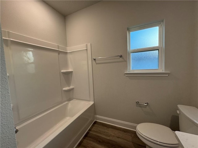 bathroom with hardwood / wood-style flooring, toilet, and shower / washtub combination