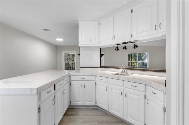 kitchen featuring white cabinetry, sink, kitchen peninsula, and a healthy amount of sunlight