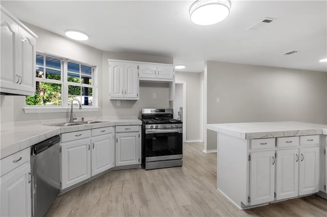 kitchen featuring kitchen peninsula, appliances with stainless steel finishes, sink, light hardwood / wood-style flooring, and white cabinetry