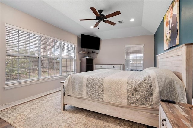 bedroom with vaulted ceiling, multiple windows, baseboards, and visible vents