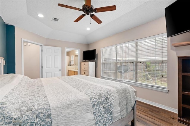 bedroom featuring dark wood-style floors, visible vents, baseboards, a tray ceiling, and recessed lighting