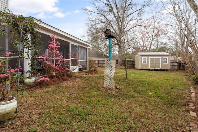 view of yard featuring an outbuilding, a storage unit, a fenced backyard, and a sunroom