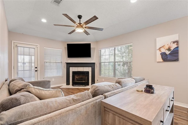 living area featuring visible vents, a healthy amount of sunlight, wood finished floors, and a ceiling fan