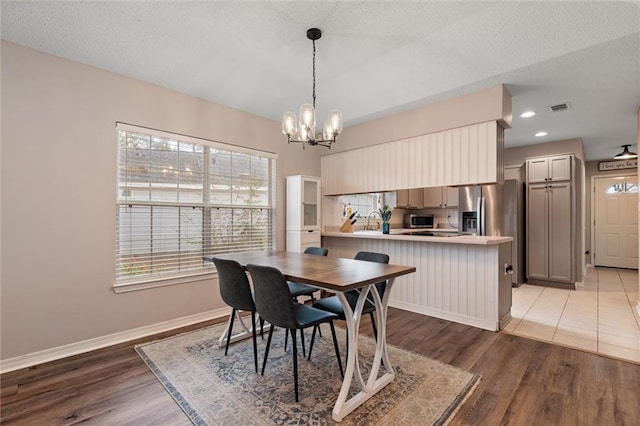 dining area featuring an inviting chandelier, baseboards, visible vents, and light wood-type flooring