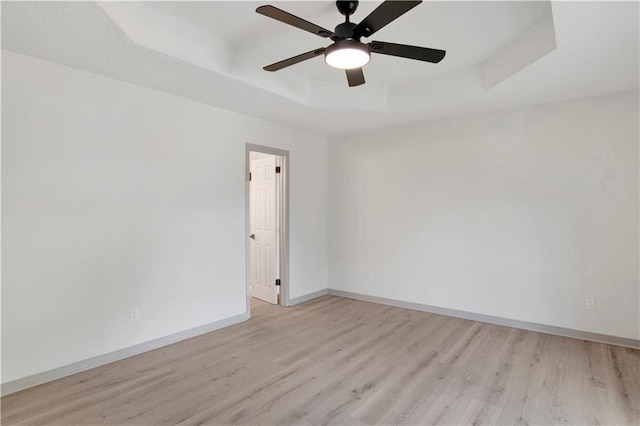 spare room featuring light hardwood / wood-style flooring, a raised ceiling, and ceiling fan