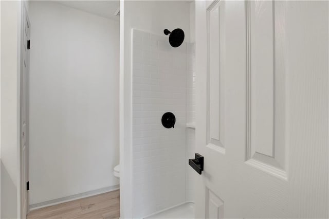 details featuring a tile shower, hardwood / wood-style floors, and toilet