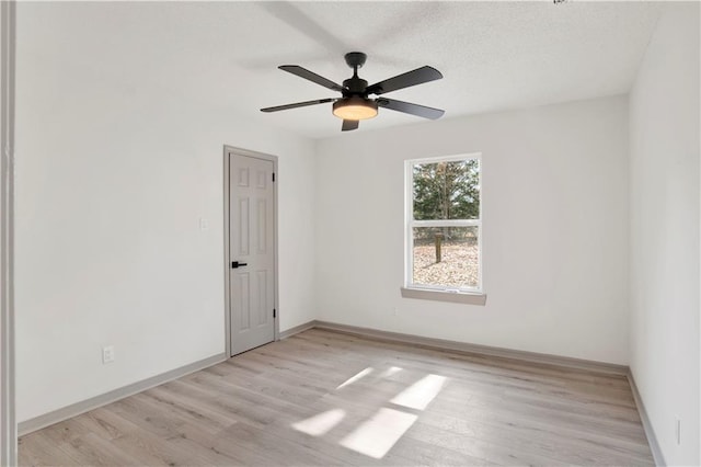 spare room with a textured ceiling, ceiling fan, and light wood-type flooring