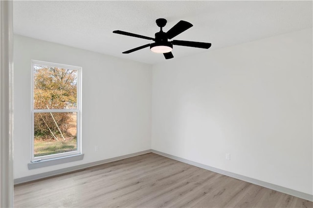 spare room featuring ceiling fan, light hardwood / wood-style flooring, and a wealth of natural light