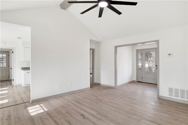 unfurnished living room with light hardwood / wood-style flooring, beam ceiling, a wealth of natural light, and high vaulted ceiling