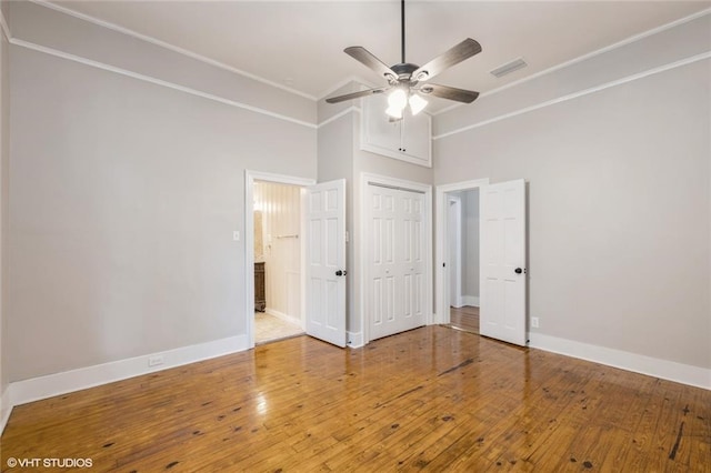 unfurnished bedroom with a towering ceiling, hardwood / wood-style flooring, and ceiling fan