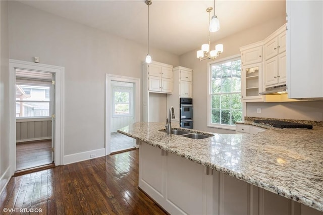 kitchen featuring light stone countertops, dark wood-type flooring, decorative light fixtures, a notable chandelier, and white cabinets