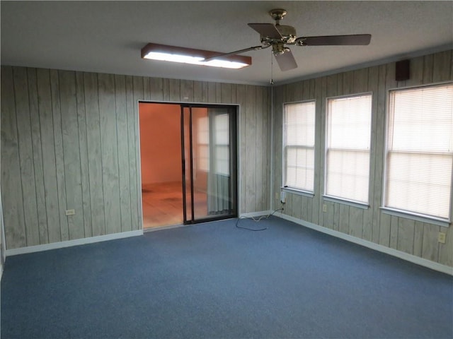 spare room with carpet, wooden walls, and ceiling fan