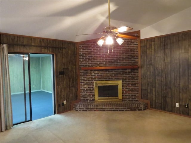 unfurnished living room featuring a brick fireplace, carpet, lofted ceiling, and wooden walls