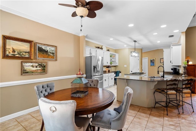 tiled dining area with ornamental molding, sink, and ceiling fan