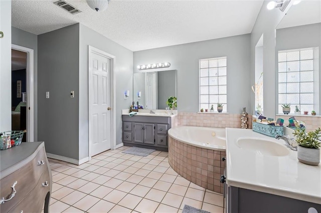 bathroom featuring a textured ceiling, visible vents, a whirlpool tub, and a sink