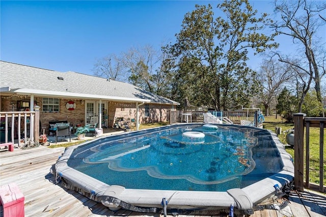 view of pool with a wooden deck and fence