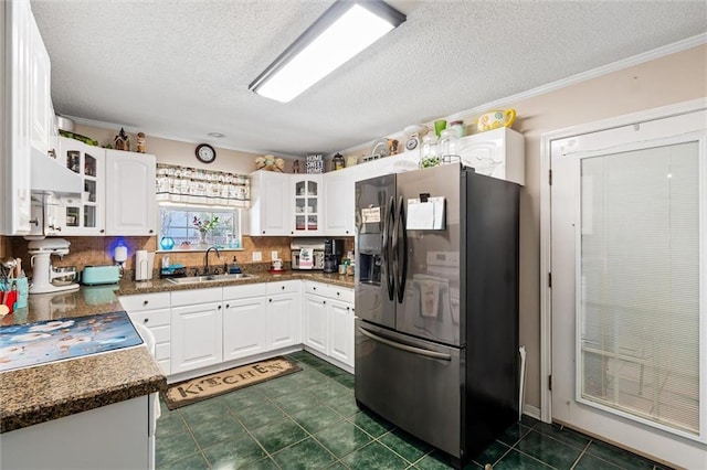 kitchen featuring a sink, glass insert cabinets, white cabinetry, dark countertops, and fridge with ice dispenser