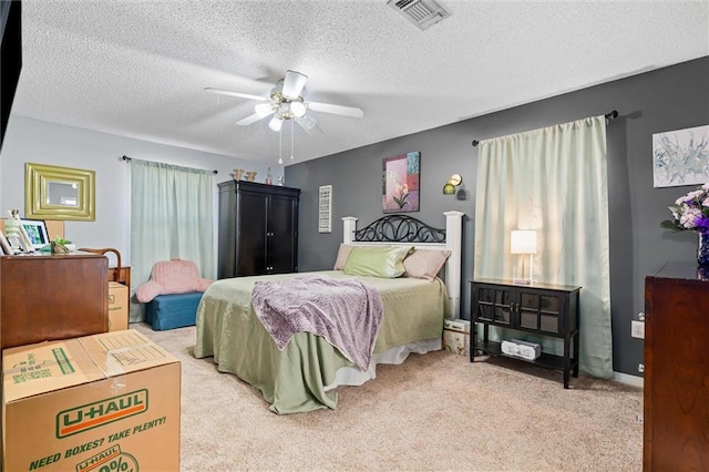 bedroom with visible vents, carpet, a ceiling fan, and a textured ceiling