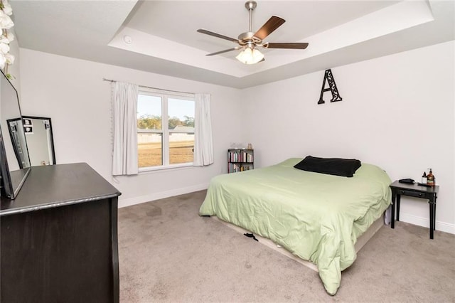 carpeted bedroom featuring a raised ceiling and ceiling fan