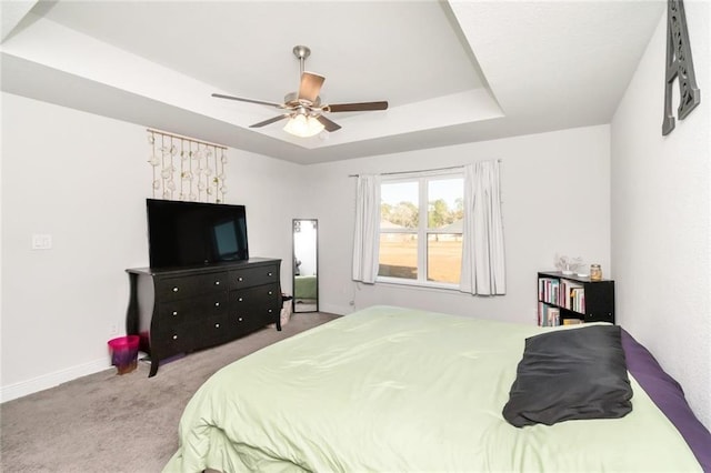 carpeted bedroom with ceiling fan and a tray ceiling