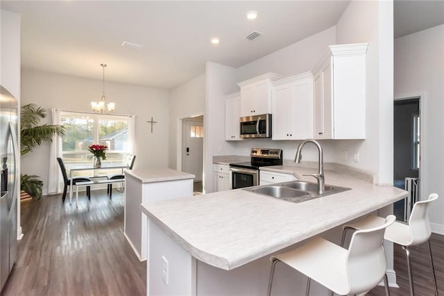 kitchen with sink, hanging light fixtures, a kitchen island, kitchen peninsula, and stainless steel appliances