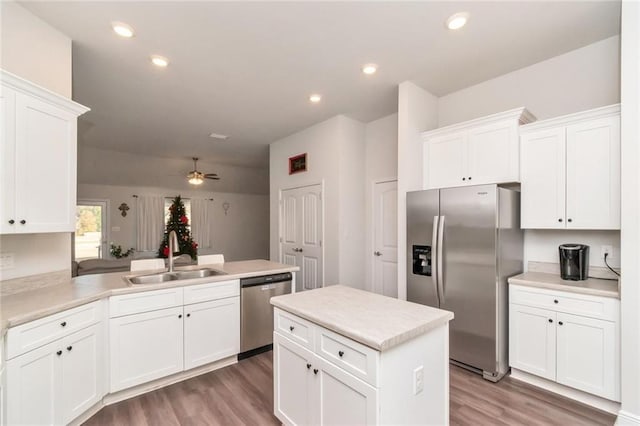 kitchen with appliances with stainless steel finishes, ceiling fan, sink, light hardwood / wood-style flooring, and white cabinets