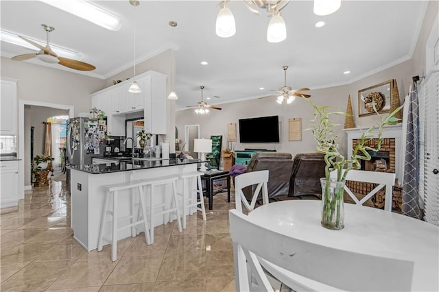 interior space with white cabinets, hanging light fixtures, stainless steel fridge, ornamental molding, and a fireplace