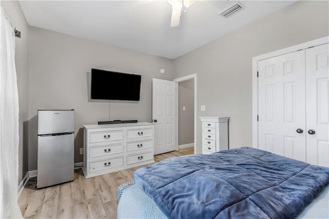 bedroom with stainless steel fridge, light wood-type flooring, a closet, and ceiling fan