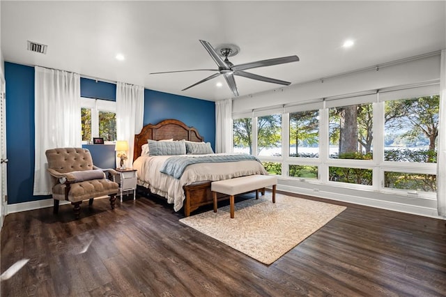 bedroom with multiple windows, dark wood-type flooring, and ceiling fan