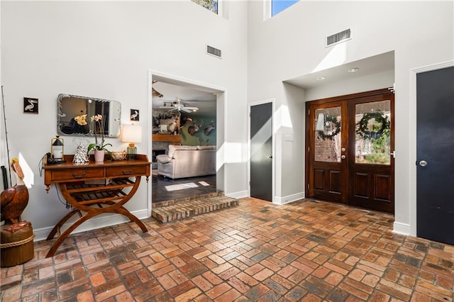 entryway featuring french doors, ceiling fan, and a high ceiling