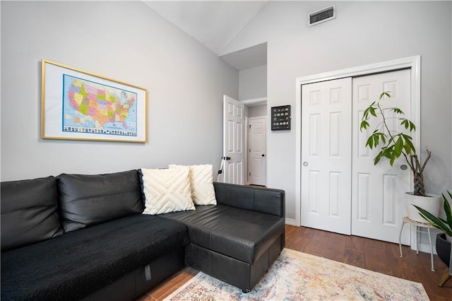 living room featuring lofted ceiling, dark wood-type flooring, and visible vents