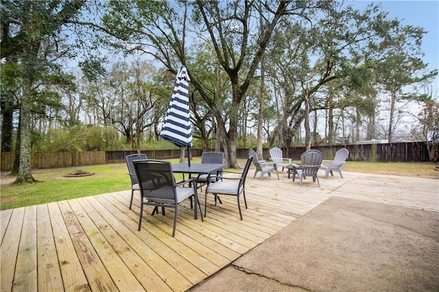 wooden terrace with an outdoor fire pit, a lawn, and a fenced backyard