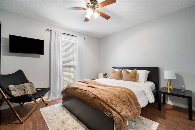 bedroom with dark wood-style floors, ceiling fan, a textured ceiling, and baseboards