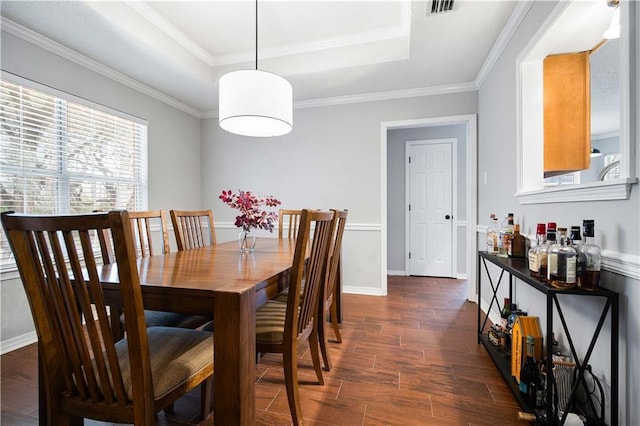 dining area with baseboards, visible vents, a raised ceiling, dark wood finished floors, and crown molding