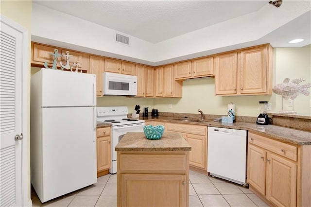 kitchen with light tile patterned floors, light brown cabinetry, a sink, and white appliances
