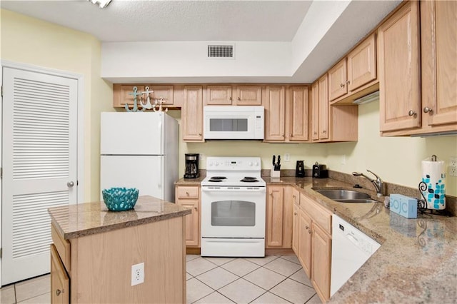 kitchen featuring visible vents, a sink, light brown cabinets, and white appliances