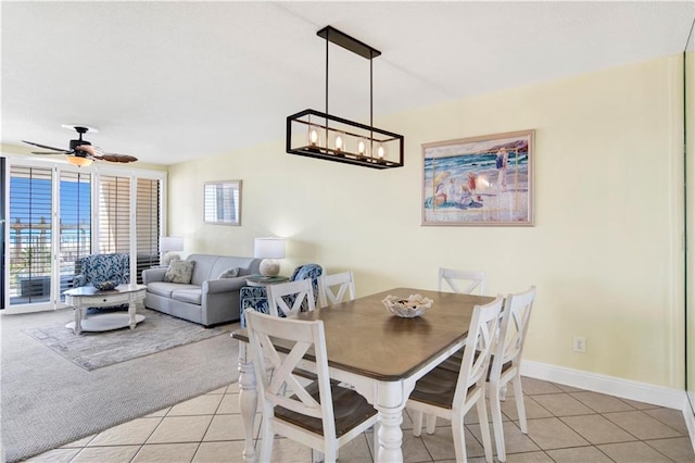 dining space with light tile patterned floors, ceiling fan with notable chandelier, light carpet, and baseboards