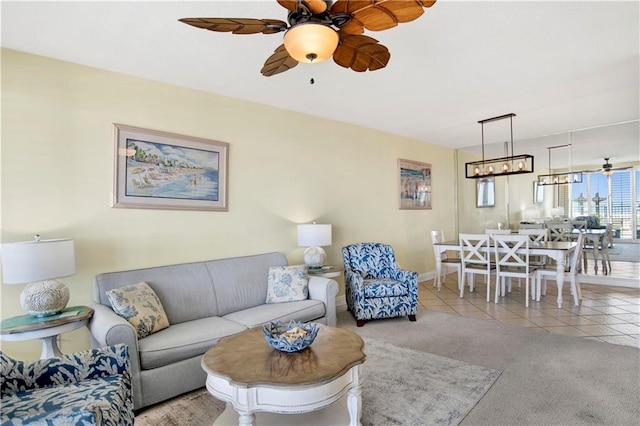 living area with carpet, a ceiling fan, tile patterned floors, and baseboards